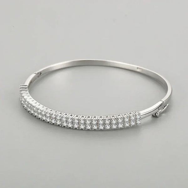 Sterling silver bangle with three rows of sparkling cubic zirconia stones on a grey background