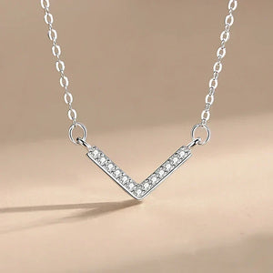 Prism Glow Pendant - TM & CO. JEWELS -Silver V-shaped necklace with small crystals on a beige backgroundز