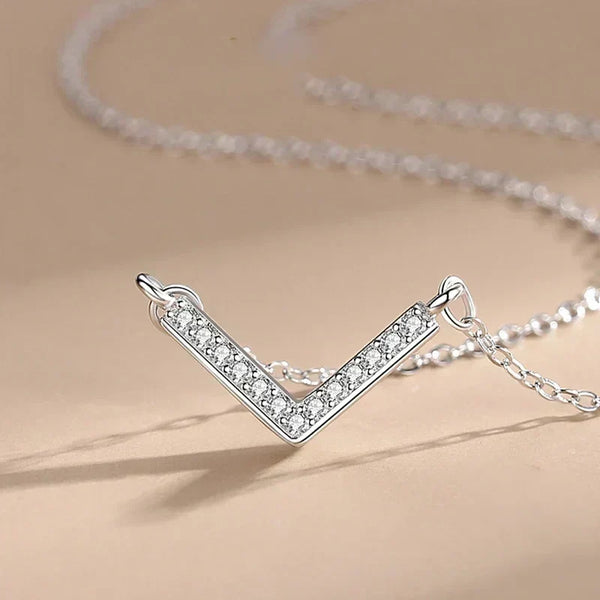Silver V-shaped necklace with clear stones on a beige background-Prism Glow Pendant - TM & CO. JEWELS 