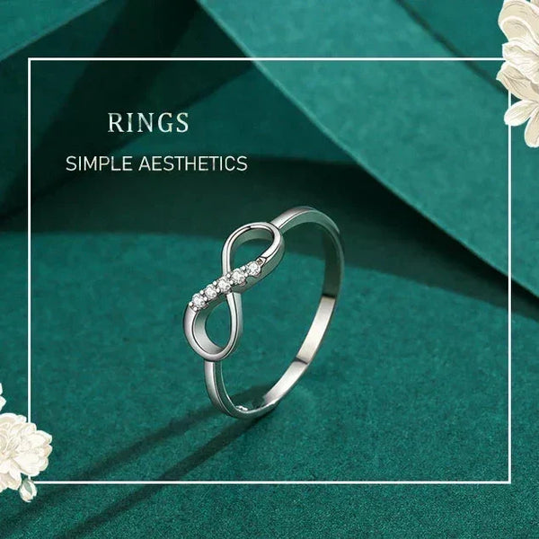 Silver ring with infinity design on a teal background with floral elements