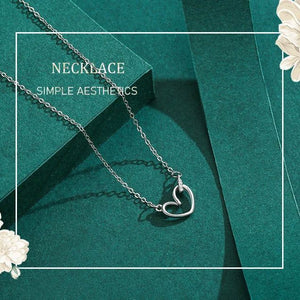 Silver necklace with a heart pendant on a green background