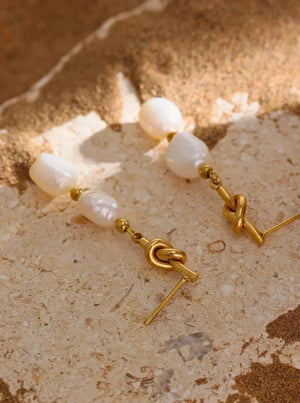 Pearl earrings with gold hooks on a textured surface