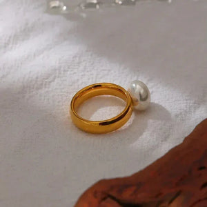 18K gold-plated ring with single pearl accent on white fabric background
