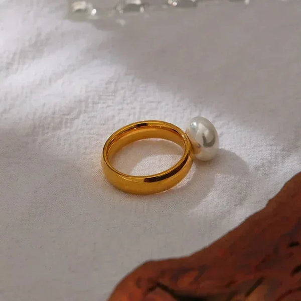 18K gold-plated ring with single pearl accent on white fabric background