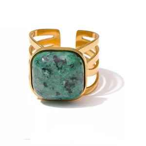 Gold bracelet with a green stone on a white background