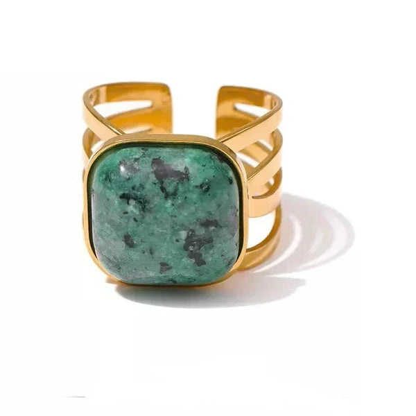 Gold bracelet with a green stone on a white background
