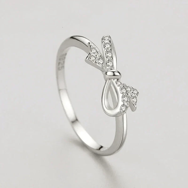 Silver ring with bow design on a light gray background