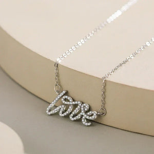 Silver 'love' necklace on a beige background