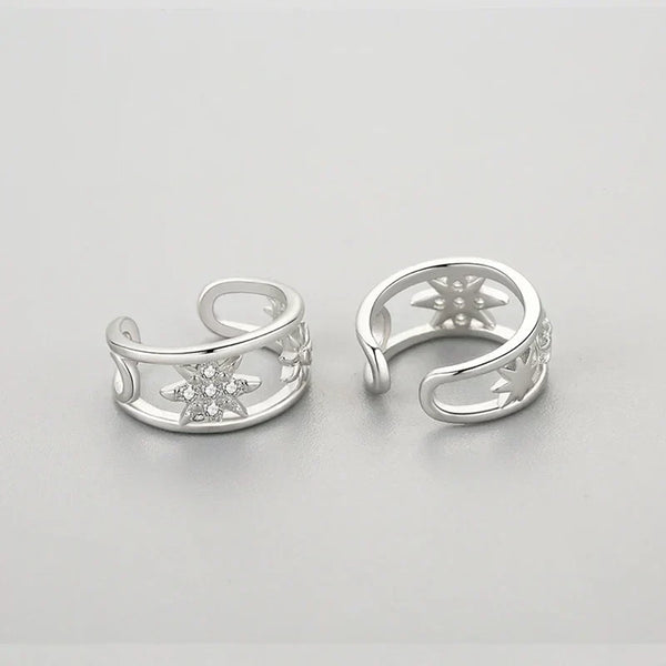 Pair of silver open earrings with star designs on a light gray background