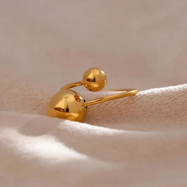 18K gold-plated open ring with two polished spheres on soft beige fabric