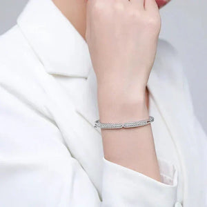 Silver bracelet on a person's wrist with a plain background-Ava Heart Bands - TM & CO. JEWELS 