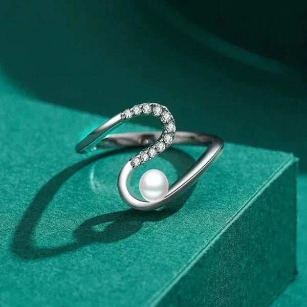 Silver ring with a pearl on a green surface