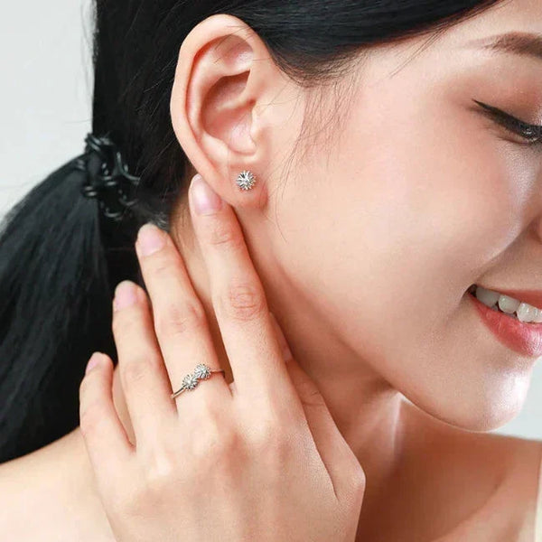 Woman wearing silver earrings and ring, smiling.