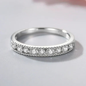 Sterling silver ring with row of round cut clear stones on a reflective surface