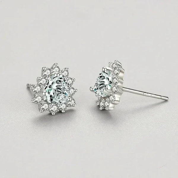 Pair of silver earrings with clear gemstones on a light gray background