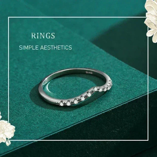 Silver ring with small stones on a green surface with floral decorations