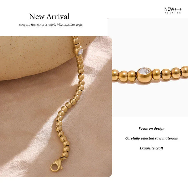 18K gold-plated beaded bracelet with single clear gem on geometric display
