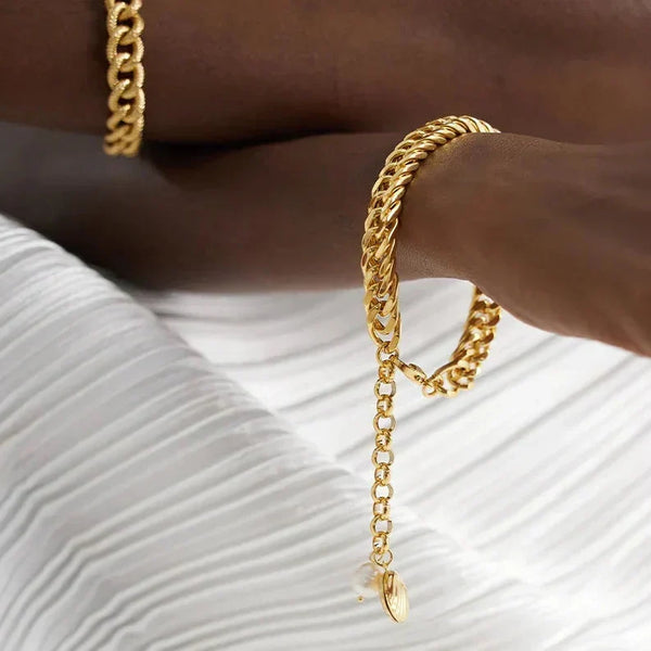 Gold chain bracelet on a wrist with a white textured background