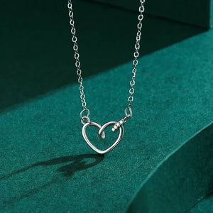Silver heart-shaped necklace on a green background