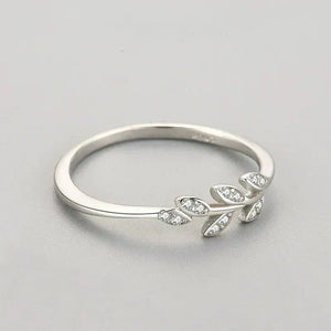 Sterling silver ring with leaf design and small clear gemstones on light background