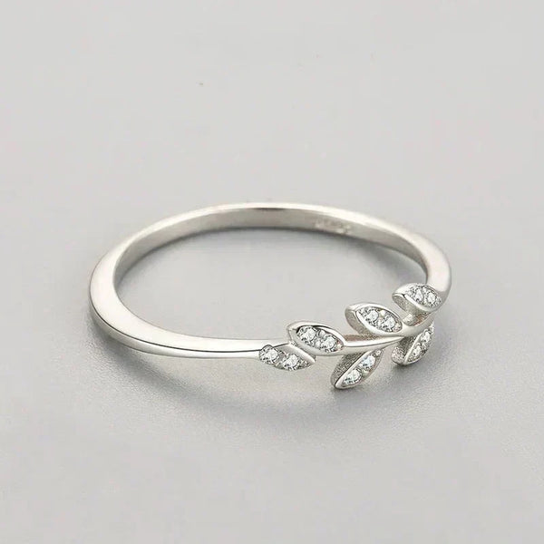 Sterling silver ring with leaf design and small clear gemstones on light background