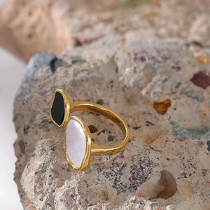 Gold-plated open ring with black and white stones on textured surface