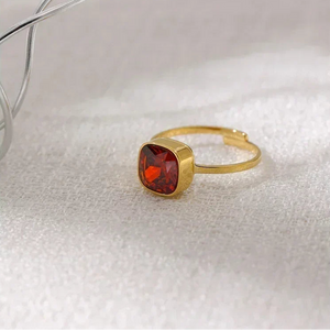 18K gold-plated ring with square red gemstone on textured white surface