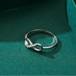 Silver infinity ring on a teal surface with 'Real Shotshow' text above.