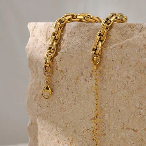 Gold chain necklace on a textured stone surface