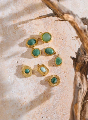 Gold earrings with green gemstones on a textured surface