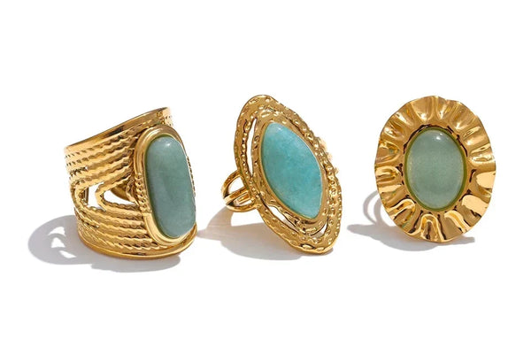 Three gold rings with turquoise stones on a white background