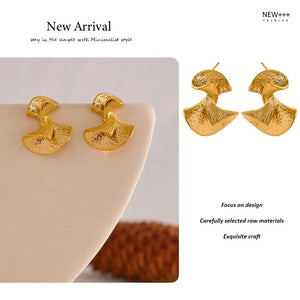 Gold earrings on a beige surface with 'NEW++' branding and text about design and craftsmanship.