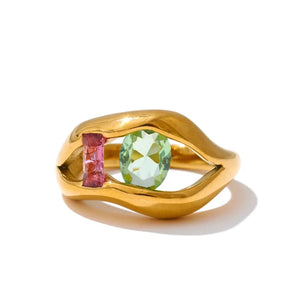 Gold ring with green and pink gemstones on a white background