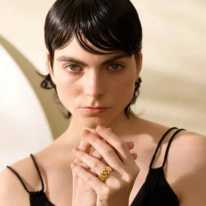 Woman wearing a chunky gold-plated statement ring and black sleeveless top
