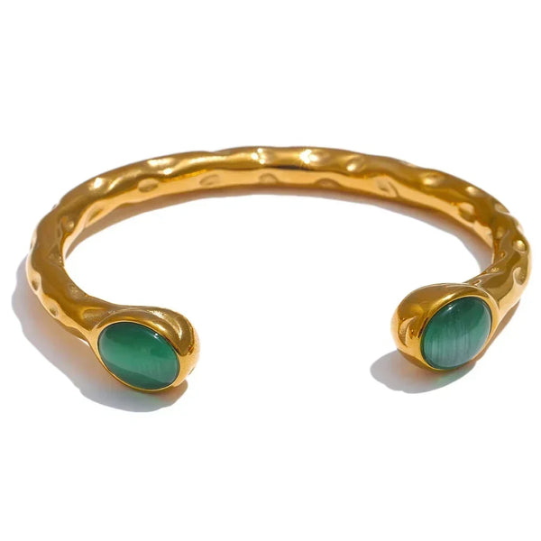 Gold bracelets with colorful stones on a textured surface, branded as Vogue.