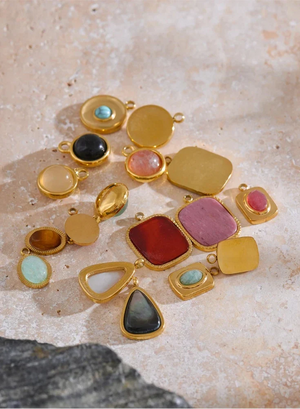 Collection of colorful gemstone pendants on a textured surface