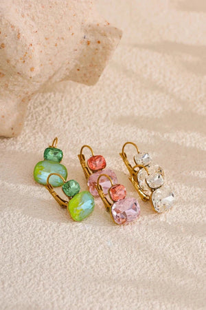 Colorful earrings on a textured beige surface