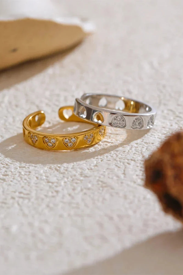Gold and silver rings with heart designs on a textured surface
