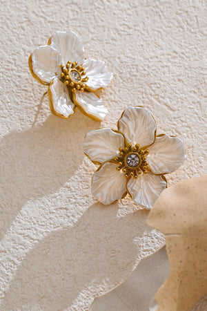 Floral earrings with gold accents on a textured beige background