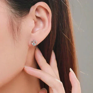 Close-up of a person wearing a silver earring with a clear gemstone.