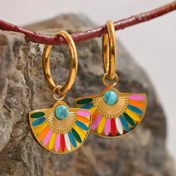 Colorful earrings with gold hoop design hanging on a branch.