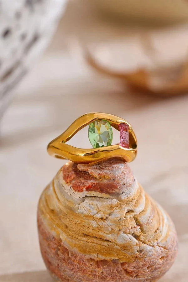 Gold ring with a green gemstone on a textured surface