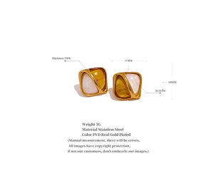 A pair of gold-plated square stud earrings with white and gold abstract inlay designs, shown with dimension.
