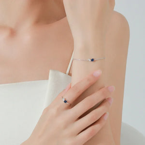 Woman wearing the Capri Twilight Jewelry Set featuring a blue gemstone ring and bracelet.