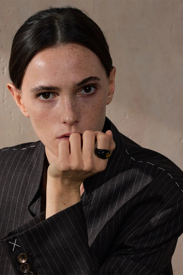 Person wearing a black pinstripe suit with a neutral background