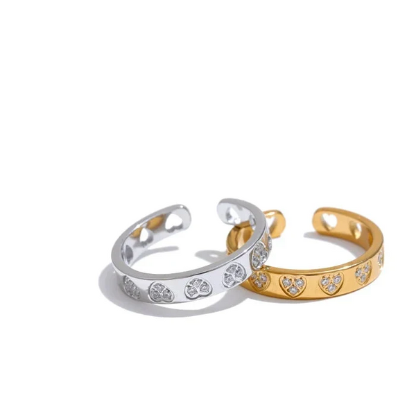 Two open rings, one silver and one gold, with heart and paw print designs on a white background.