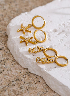 Set of gold earrings on a white stone surface