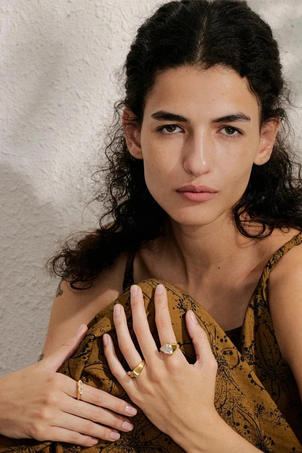 Woman wearing multiple rings on her fingers against a neutral background