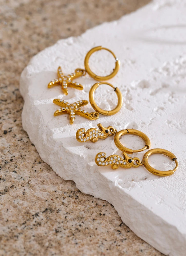 Gold earrings on a white stone surface