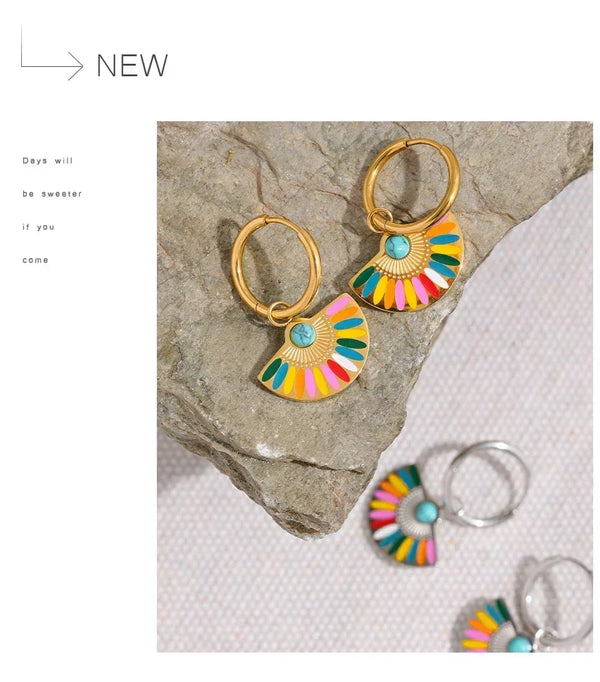 Colorful earrings with gold accents on a stone surface
